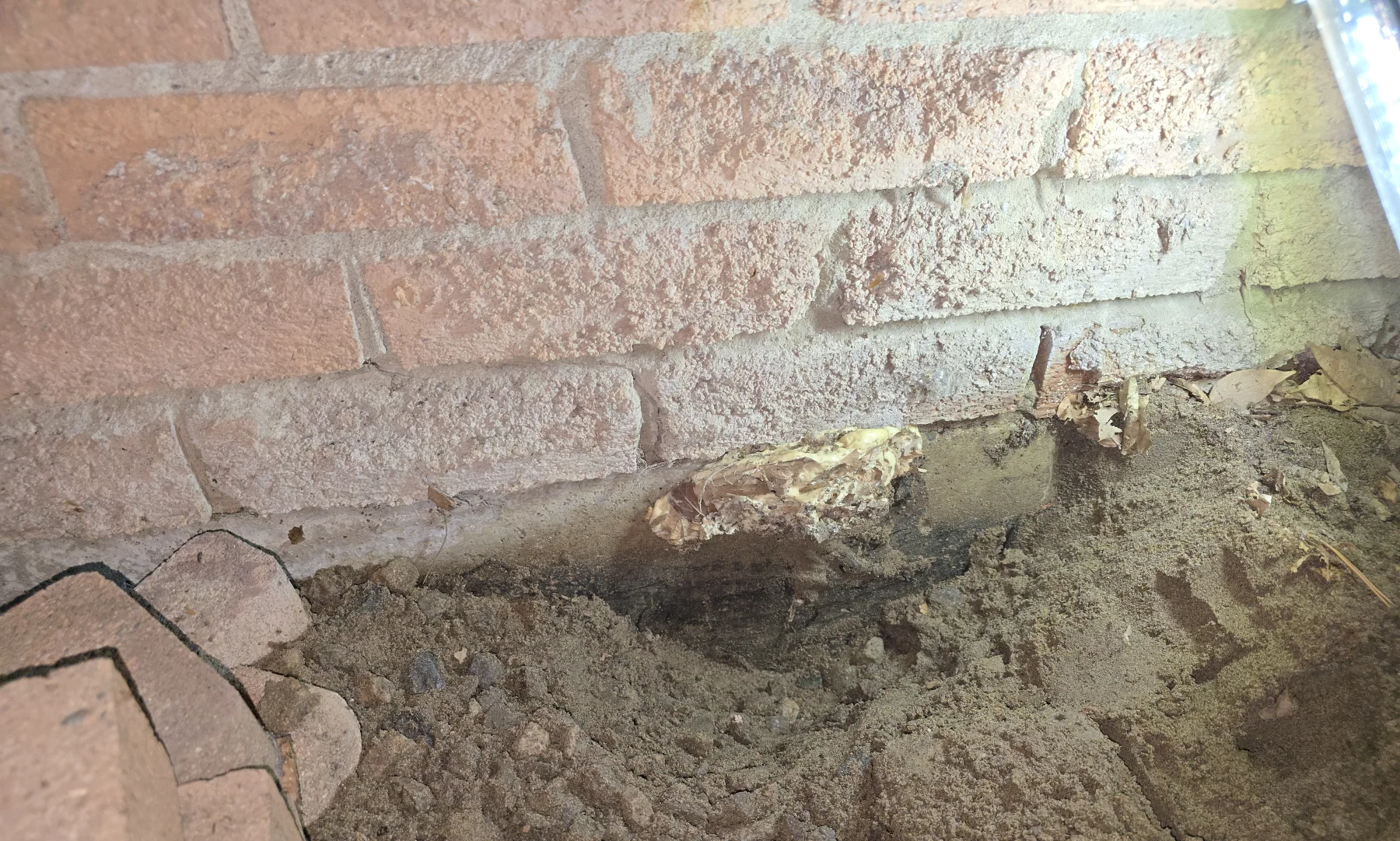Foundation and masonry conditions exposed beside soil and moisture staining